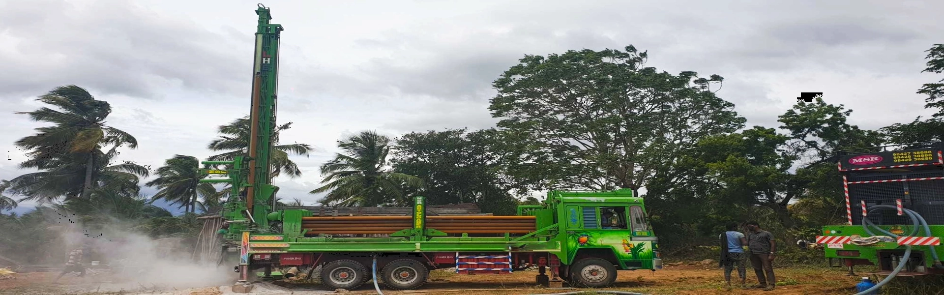 On open land, a green borewell machine in the process of drilling underground for water extraction