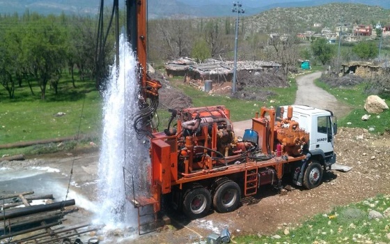 A truck spraying water from a pump after well drilling, borewell cleaning/flushing process.