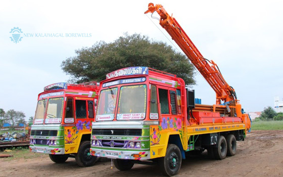 Two lively borewell trucks are stationed along the roadside, embellished with vibrant colors.