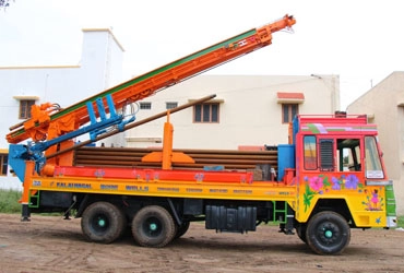 A specialized truck featuring a crane on top, utilized for efficient drilling of 4.5 borewells 