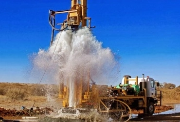 A drilling rig sprays water over the ground to aid in the drilling and borewell cleaning processes.